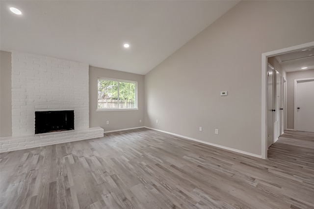 unfurnished living room featuring a fireplace, lofted ceiling, and light hardwood / wood-style floors