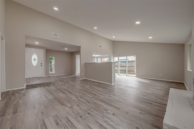 unfurnished living room with high vaulted ceiling and light hardwood / wood-style floors