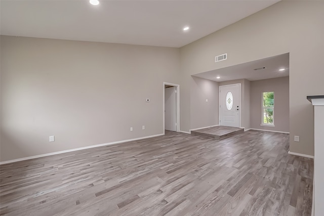 unfurnished living room featuring high vaulted ceiling and light hardwood / wood-style floors