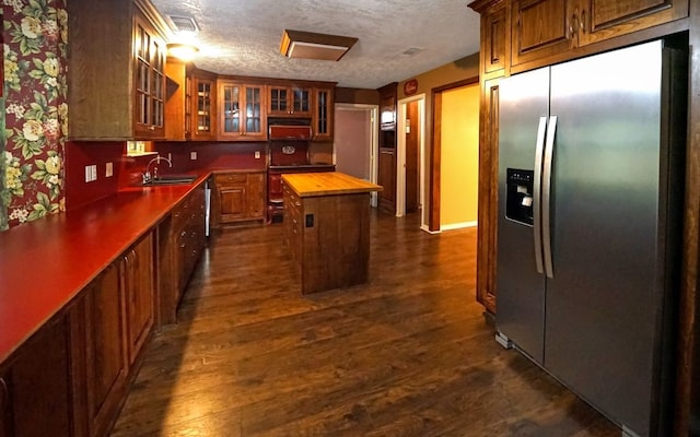 kitchen featuring a textured ceiling, butcher block countertops, dark hardwood / wood-style flooring, a center island, and appliances with stainless steel finishes