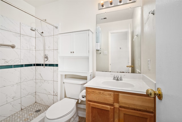 bathroom featuring toilet, a tile shower, and vanity