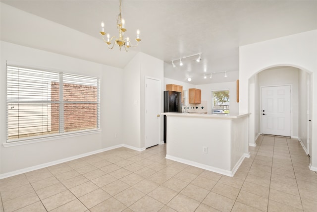 kitchen with a chandelier, light tile patterned flooring, hanging light fixtures, light brown cabinets, and black fridge