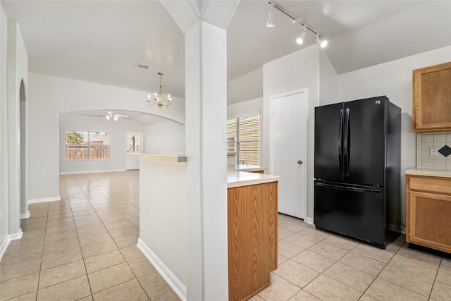 kitchen featuring ceiling fan with notable chandelier, backsplash, lofted ceiling, black fridge, and light tile patterned flooring