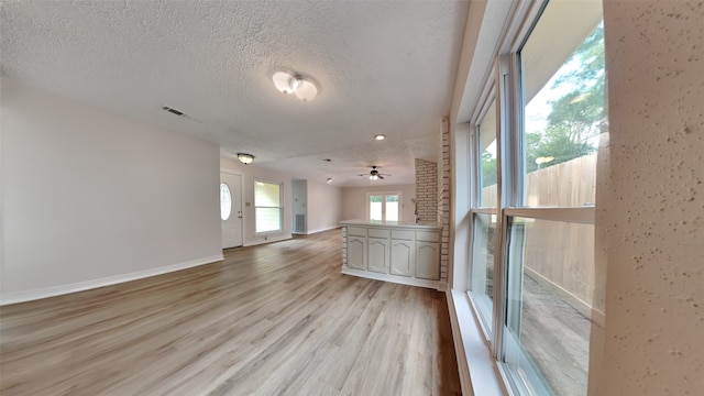 unfurnished room featuring light wood-type flooring, ceiling fan, and a textured ceiling