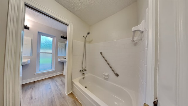 bathroom featuring a textured ceiling, bathing tub / shower combination, and hardwood / wood-style floors