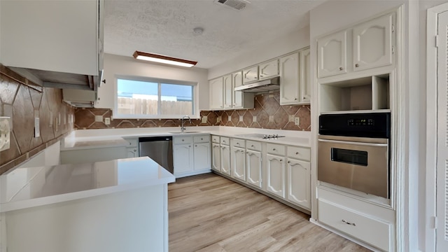 kitchen featuring white cabinetry, tasteful backsplash, stainless steel appliances, light wood-type flooring, and sink