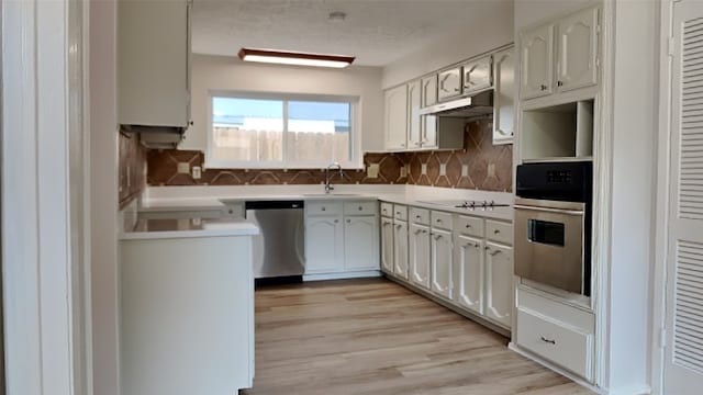 kitchen with appliances with stainless steel finishes, backsplash, light hardwood / wood-style flooring, and white cabinets