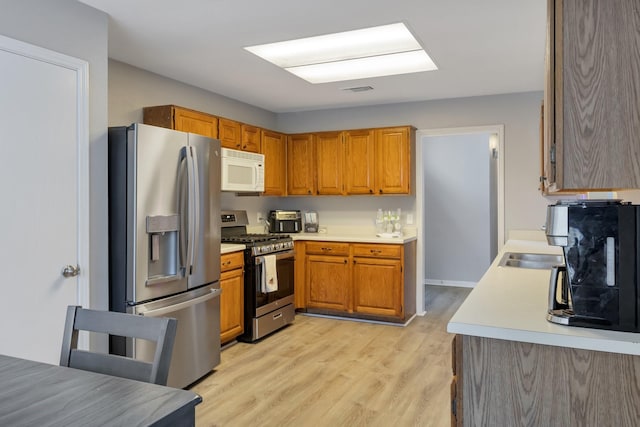 kitchen with light hardwood / wood-style flooring and appliances with stainless steel finishes