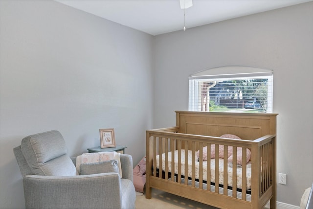 bedroom with a nursery area and ceiling fan