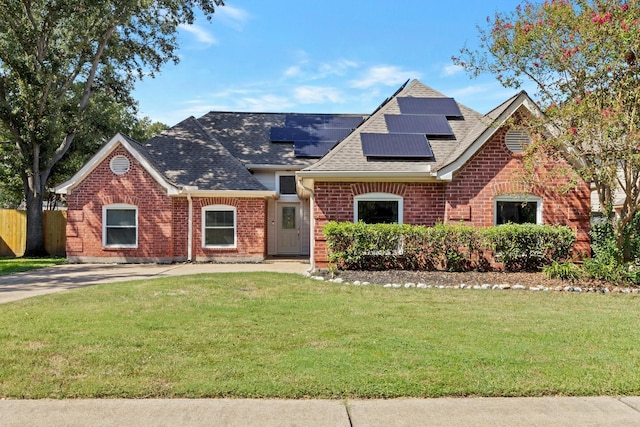 view of front of home with solar panels and a front lawn