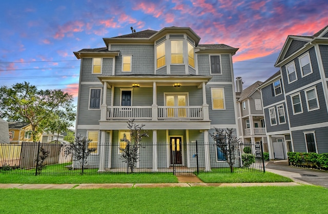 view of front facade featuring a balcony, a porch, and a lawn