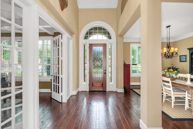 foyer with dark wood-type flooring, an inviting chandelier, and crown molding