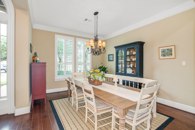 dining space with dark wood-type flooring, ornamental molding, and a notable chandelier