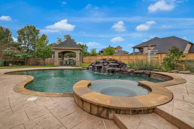 view of swimming pool featuring pool water feature, a gazebo, and an in ground hot tub