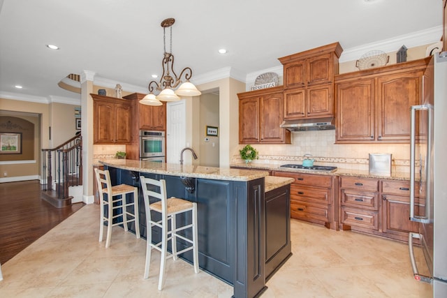 kitchen featuring an inviting chandelier, crown molding, a center island with sink, and pendant lighting