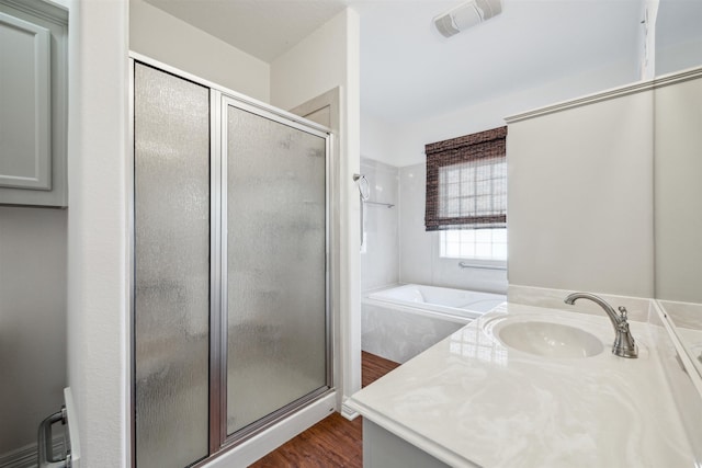 bathroom with hardwood / wood-style floors, independent shower and bath, and vanity