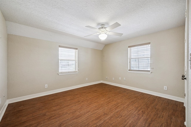 unfurnished room featuring lofted ceiling, dark wood-type flooring, ceiling fan, and a textured ceiling