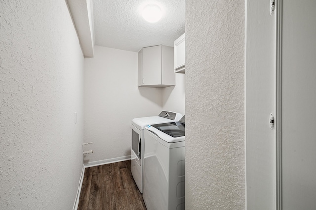 washroom featuring dark wood-type flooring, washer and dryer, cabinets, and a textured ceiling