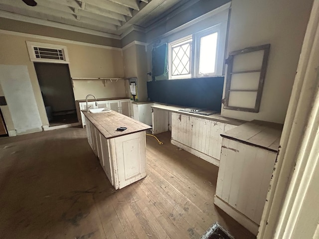 kitchen with white cabinetry, wood-type flooring, a kitchen island, and sink