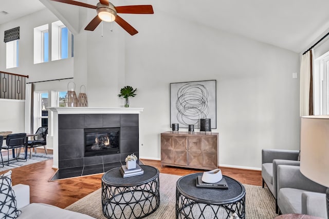 living room with a fireplace, hardwood / wood-style flooring, high vaulted ceiling, and ceiling fan