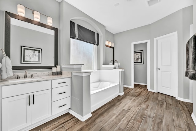 bathroom with vanity, wood-type flooring, and a bath