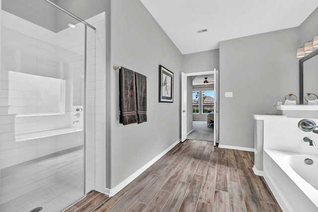 bathroom with ceiling fan, wood-type flooring, and plus walk in shower