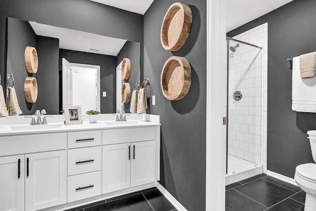 bathroom featuring toilet, vanity, a tile shower, and tile patterned flooring