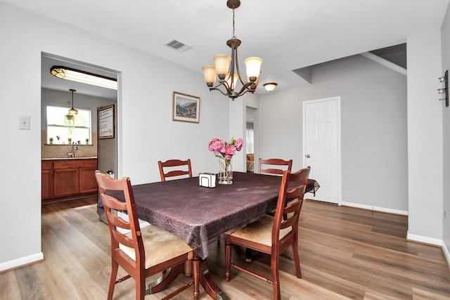 dining space featuring an inviting chandelier, wood-type flooring, and sink