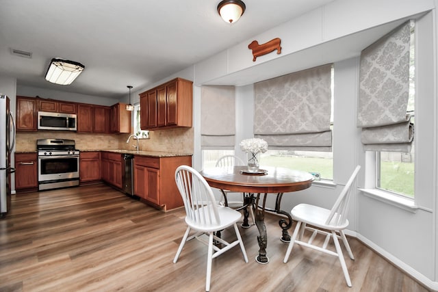 kitchen featuring pendant lighting, light stone counters, tasteful backsplash, appliances with stainless steel finishes, and dark hardwood / wood-style flooring