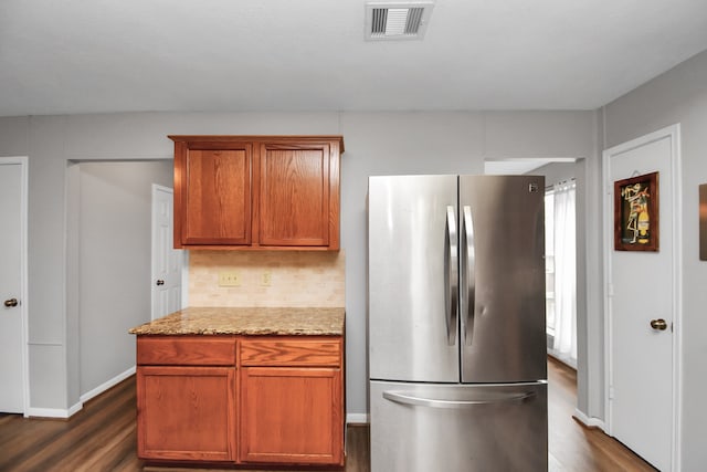 kitchen featuring stainless steel refrigerator, light stone countertops, dark wood-type flooring, and tasteful backsplash