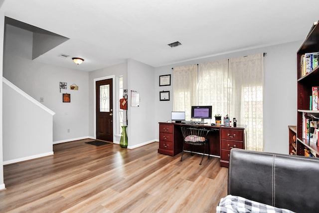 home office with built in desk, light hardwood / wood-style flooring, and plenty of natural light