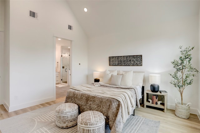 bedroom featuring light hardwood / wood-style floors, high vaulted ceiling, and ensuite bathroom