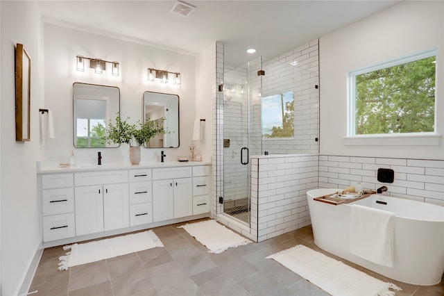 bathroom featuring vanity, tile walls, tile patterned flooring, and plus walk in shower