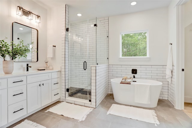 bathroom featuring vanity, independent shower and bath, tile walls, and tile patterned flooring