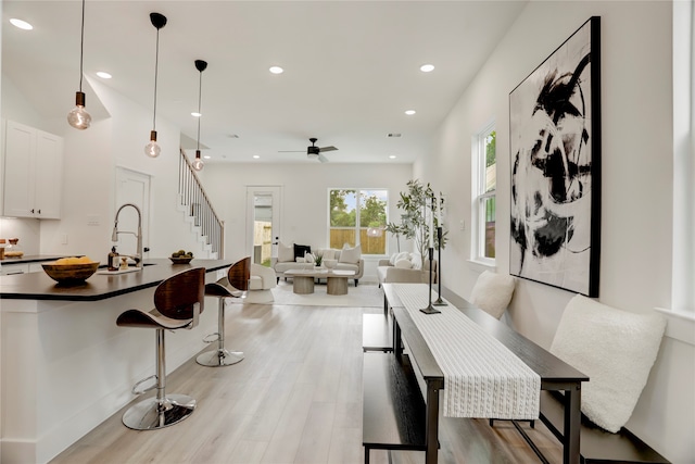 dining room with ceiling fan, sink, and light wood-type flooring