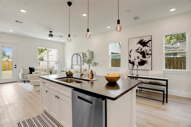 kitchen with a center island with sink, hanging light fixtures, white cabinetry, stainless steel dishwasher, and sink