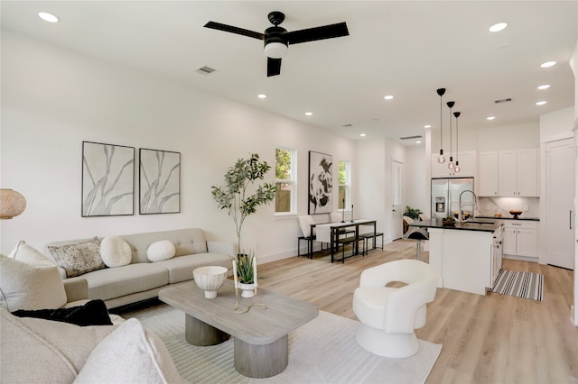 living room with sink, light wood-type flooring, and ceiling fan