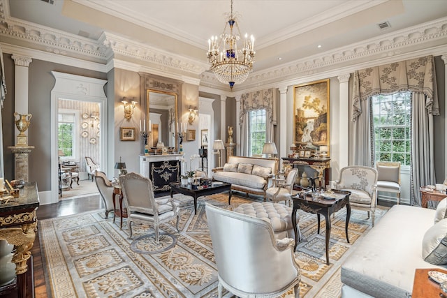 living room with crown molding, a notable chandelier, hardwood / wood-style flooring, and decorative columns