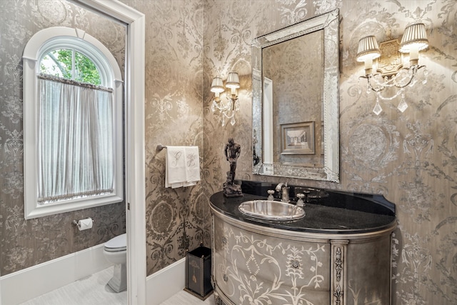 bathroom featuring vanity, toilet, and an inviting chandelier