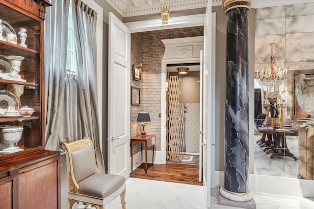 bathroom featuring hardwood / wood-style flooring, a chandelier, crown molding, and brick wall