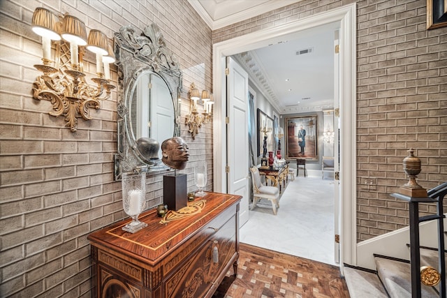 doorway to outside with crown molding, a notable chandelier, brick wall, and parquet floors