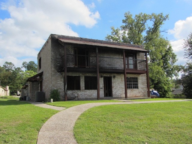 view of front of house with cooling unit, a balcony, and a front yard