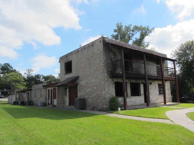 view of home's exterior with a balcony, a yard, and cooling unit