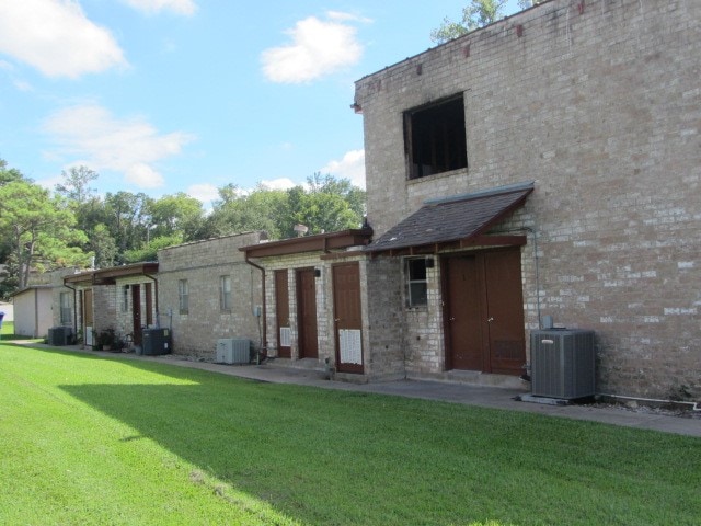 rear view of property with a lawn and central air condition unit