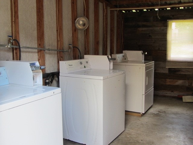 clothes washing area with separate washer and dryer and wooden walls