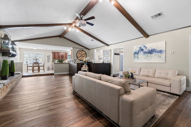 living room with a textured ceiling, lofted ceiling with beams, dark wood-type flooring, and ceiling fan