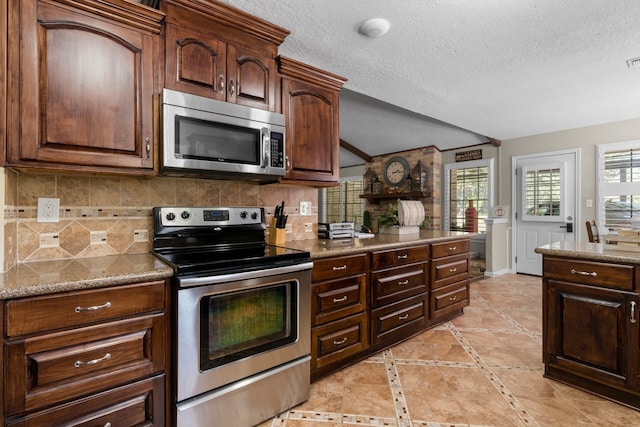 kitchen with light stone counters, backsplash, stainless steel appliances, a textured ceiling, and dark brown cabinets