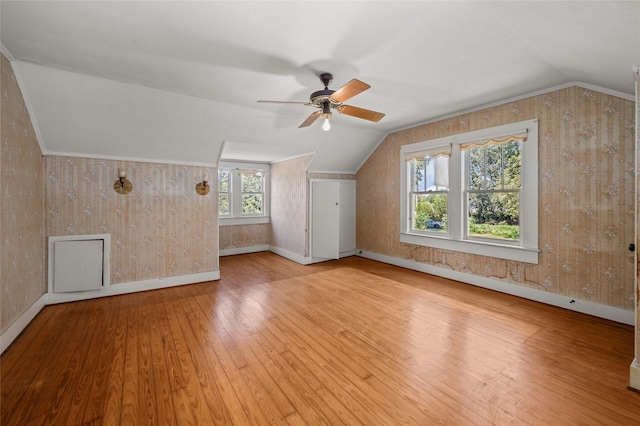 bonus room featuring a ceiling fan, hardwood / wood-style flooring, baseboards, wallpapered walls, and lofted ceiling
