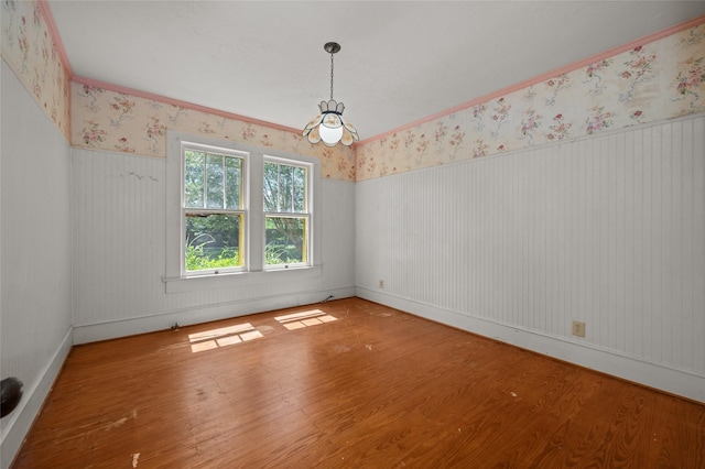 unfurnished room featuring a wainscoted wall, a chandelier, wood finished floors, and wallpapered walls
