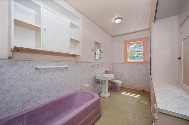 full bathroom featuring wainscoting, ornamental molding, a textured ceiling, toilet, and a washtub